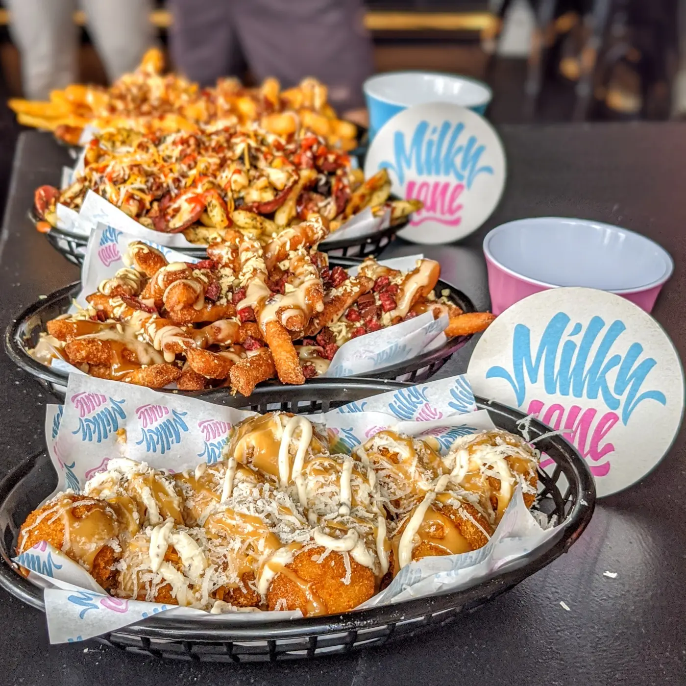 Three baskets of Milky Lane loaded fries on a table